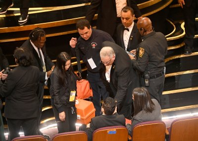 An EMT (standing, center) speaks with Rami Malek (seated, center) during the 91st Annual Academy Awards 