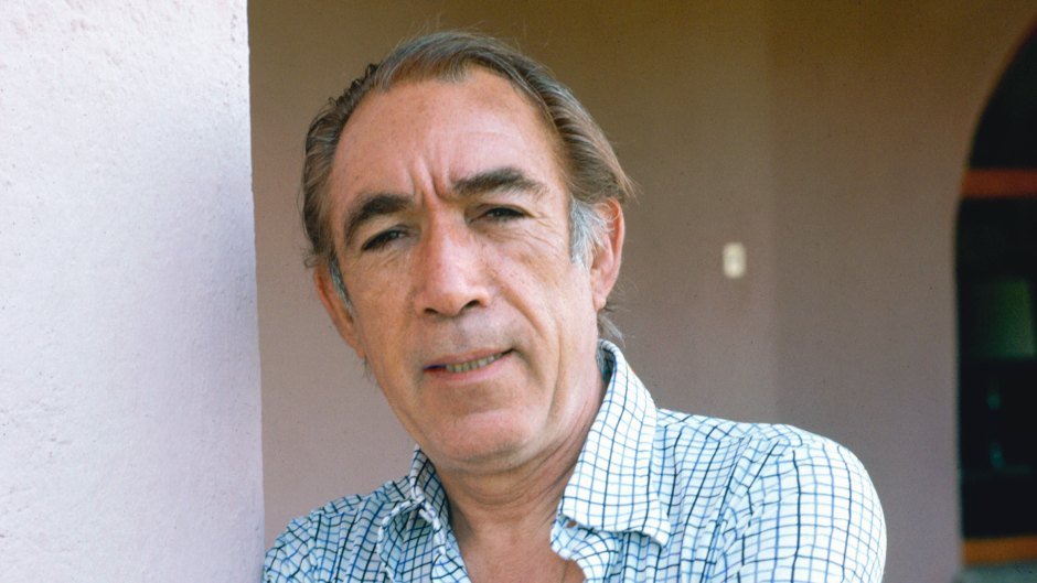 Anthony Quinn (1915-2001), poses with his arms folded across his chest, wearing a blue-and-white short-sleeved shirt, circa 1975.