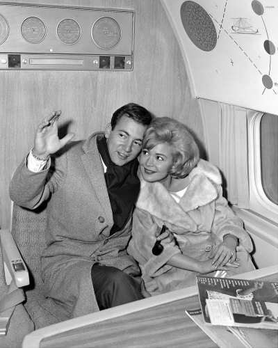 Bobby Darin, 24, the young man with the swinging tones, cuddles up to his bride, actress Sandra Dee, 18, as they fly out of International Airport for Hollywood honeymoon