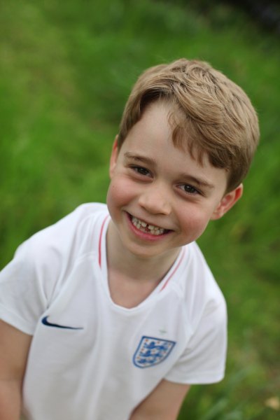 prince george smiles wearing a white soccer tee in the garden at kensington palace