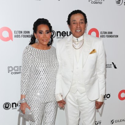 Smokey Robinson wears a white suit while posing with