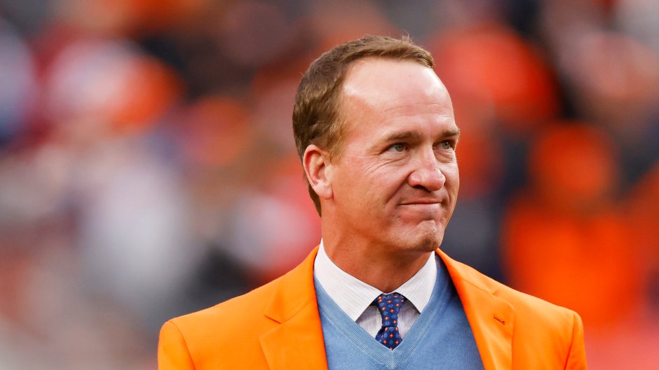 Peyton Manning wears orange blazer while holding football on field