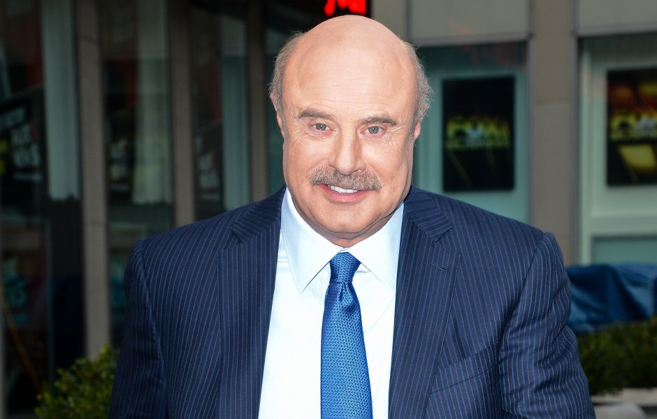 Dr. Phil walks down the street in a navy blue suit