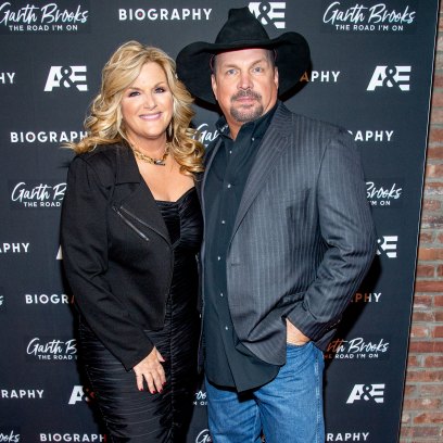 Garth Brooks wears gray suit jacket with blue jeans next to wife Trisha Yearwood