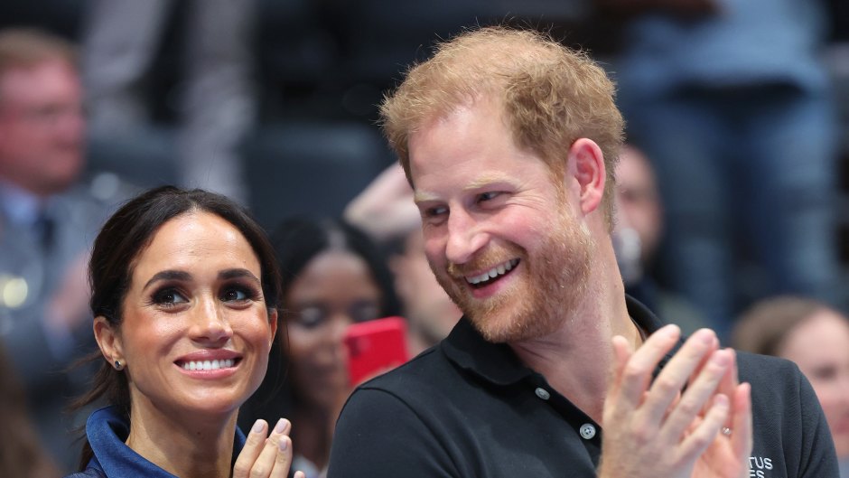 Prince Harry looks at Meghan Markle while clapping hands