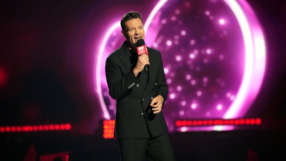 Ryan Seacrest wears black suit while holding microphone