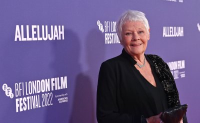 Judi Dench smiles while wearing a black suit
