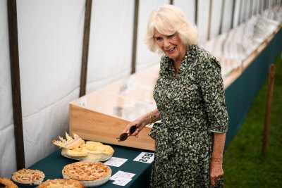 Queen Camilla reacts as she looks at a pie depicting King Charles III at Sandringham Flower Show
