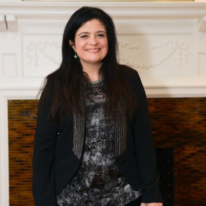 Alex Guarnaschelli smiles in a black jacket and pants