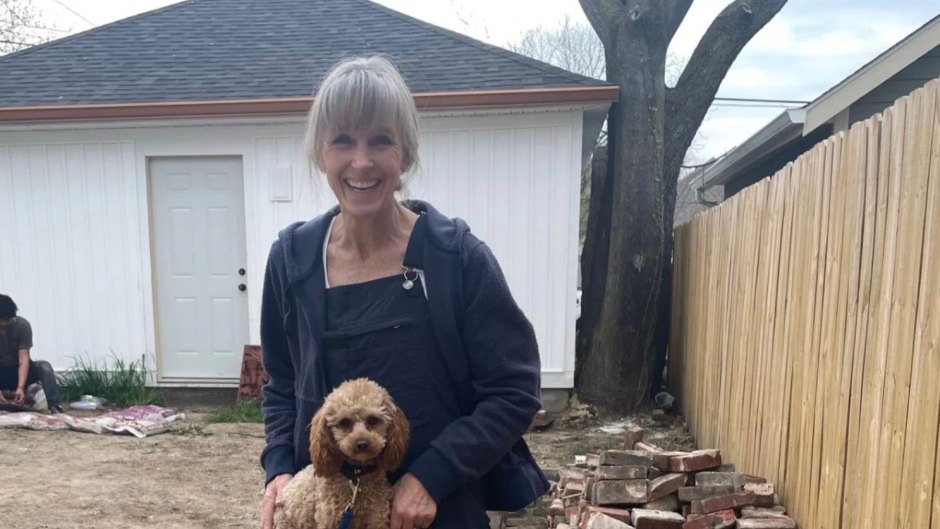 Karen E. Laine smiles while posing with two dogs outside of home