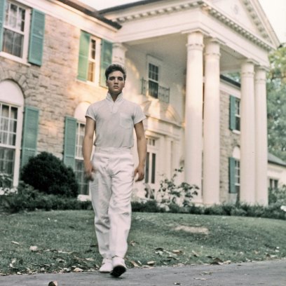 Elvis Presley stands outside of Graceland home