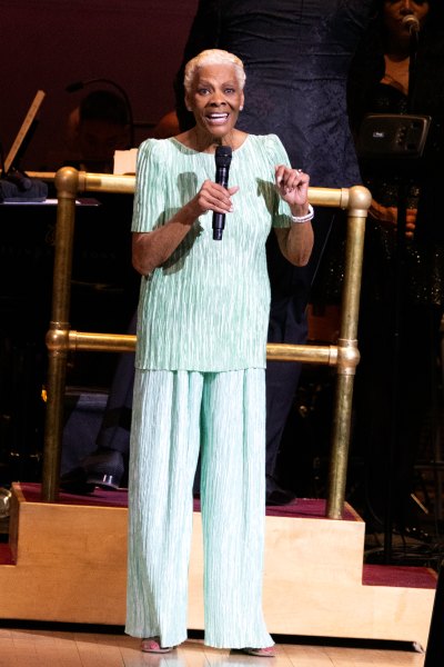 Dionne Warwick wears mint green two-piece sete while holding microphone on stage 