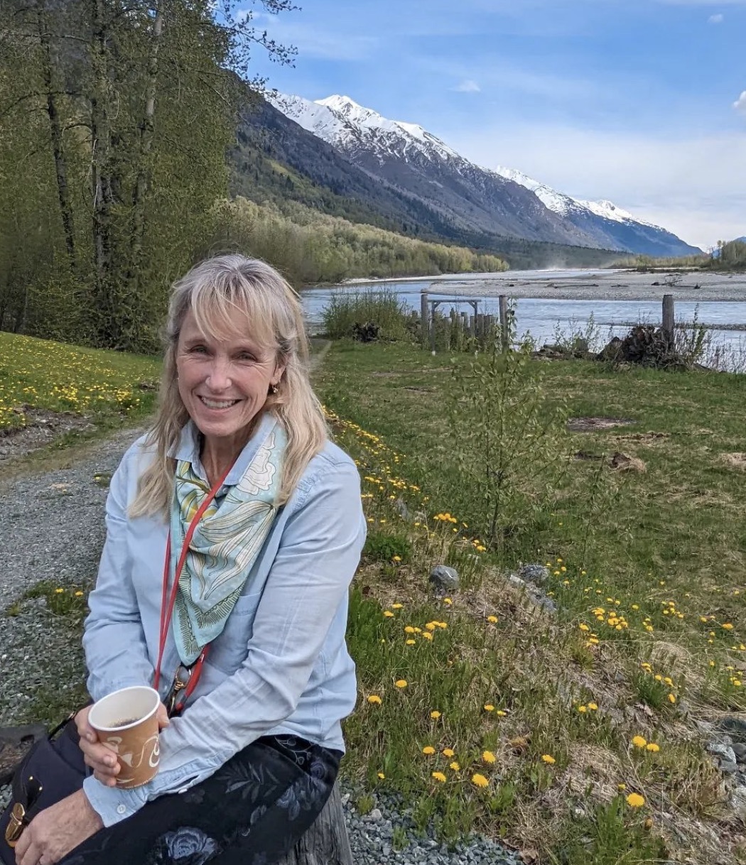 Karen E. Laine sits in front of mountain in Alaska