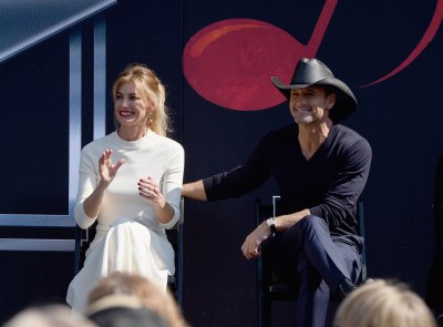Tim McGraw and Faith Hill sit side by side on stage in front of audience