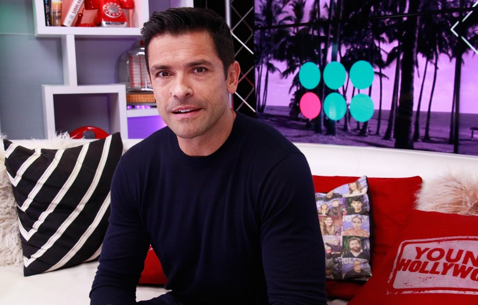 Mark Consuelos sits on coach in black sweater and pants