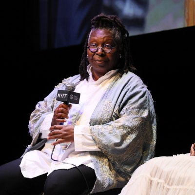 Whoopi Goldberg sits in chair and hold microphone