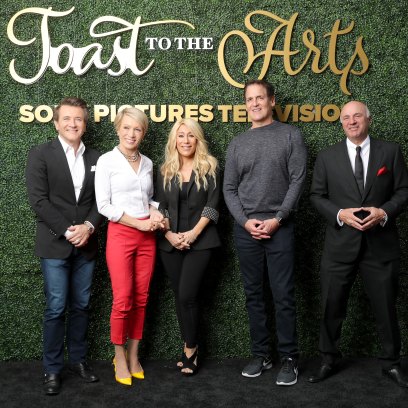The cast of Shark Tank stands together in front of green backdrop