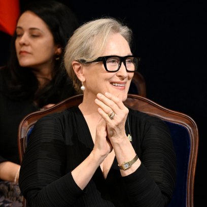 Meryl Streep claps her hands while sitting in a chair