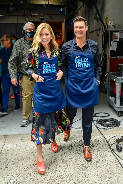 Kelly Ripa and Ryan Seacrest walk side by side wearing aprons