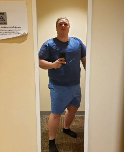 Austin Aynes wears blue top and bottoms whiile taking selfie in mirror