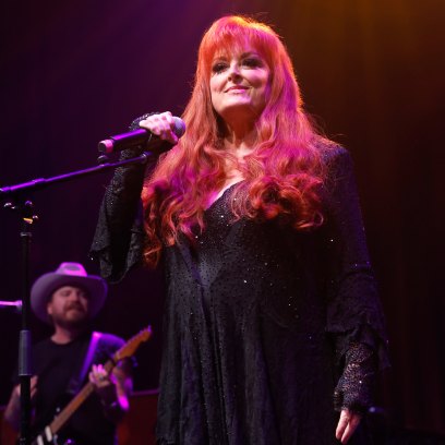 Wynonna Judd sings on stage in black outfit