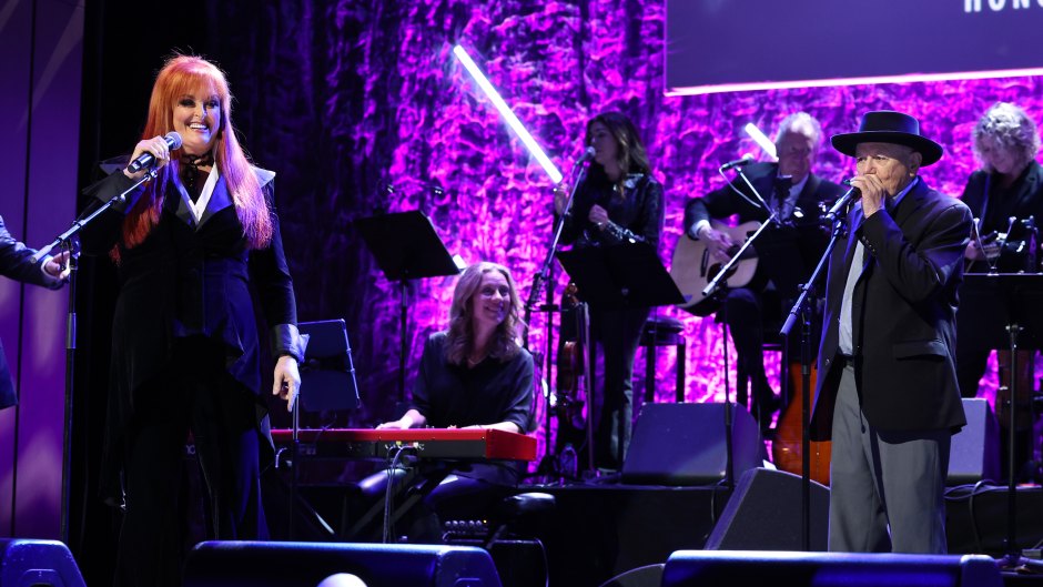 Wynonna Judd performs on stage in velvet pantsuit