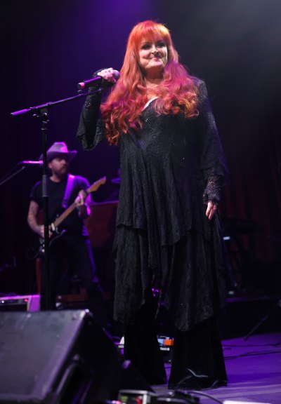 Wynonna Judd wears black outfit while singing on stage