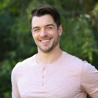 Dan Jeannotte smiles in a pink long-sleeve shirt