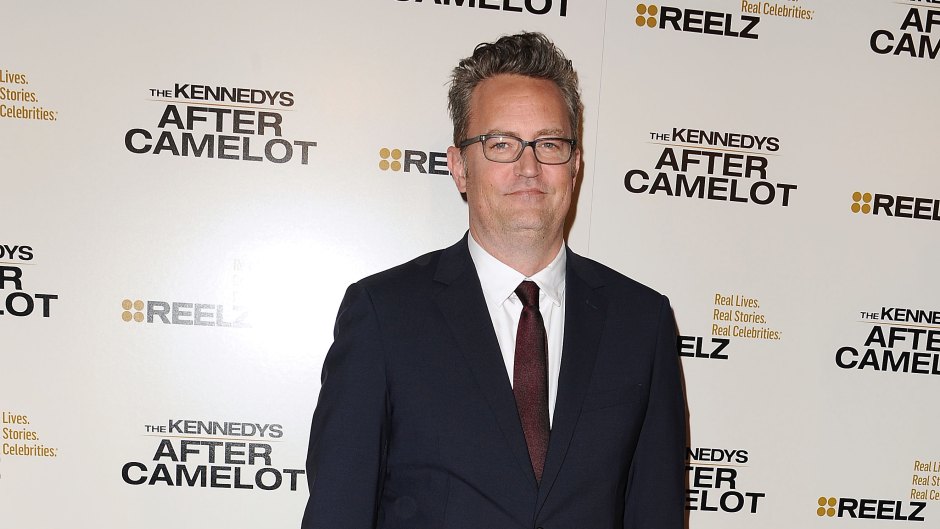 Matthew Perry stands with his hands in his pockets in a suit