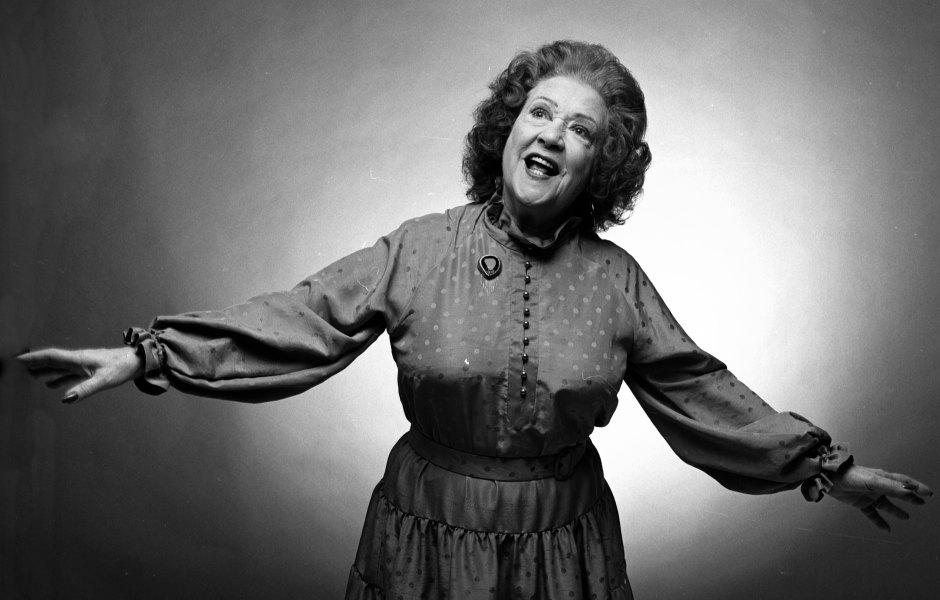 Ethel Merman smiles while wearing a long-sleeve dress