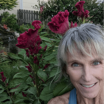 Karen E. Laine poses for selfie in front of flowers 