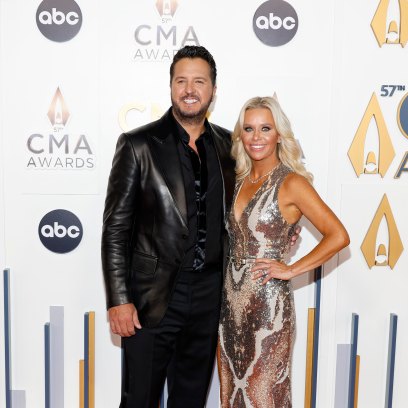 Luke Bryan stands next to wife Caroline who is wearing a gold dress