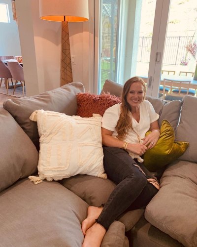 Mina Starsiak Hawk sits on couch in a T-shirt and jeans
