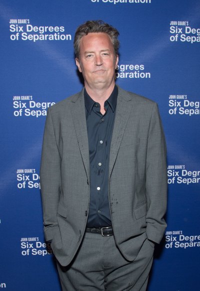 Matthew Perry wears a gray suit with hands in his pockets
