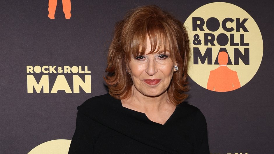Joy Behar holds black purse while wearing a black top and brown pants