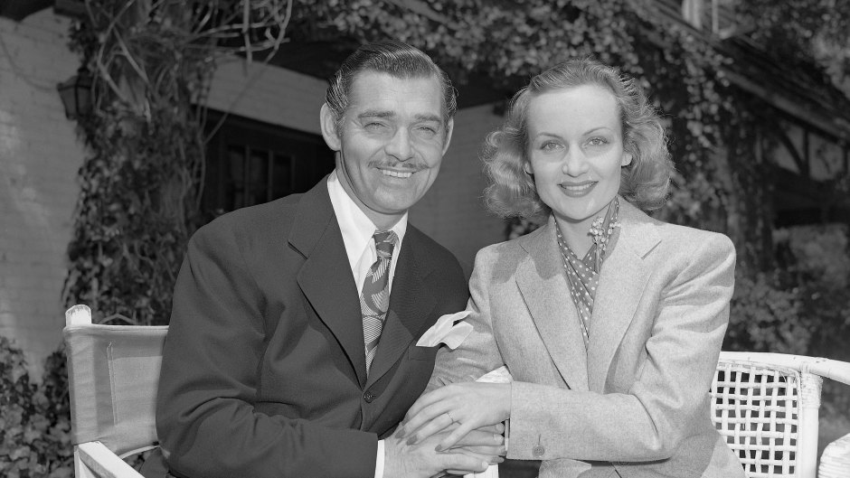 Carole Lombard and Clark Gable smile while sitting next to each other