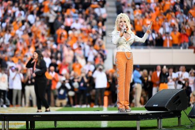 Dolly Parton performs at stadium in a silver blazer and orange pants