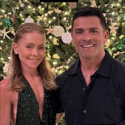 Kelly Ripa and Mark Consuelos standing in front of Christmas tree
