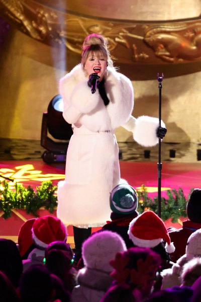Kelly Clarkson sings on stage in a white fur coat