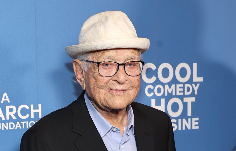 Norman Lear wears black suit and tan hat on the red carpet