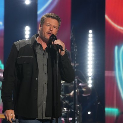 Blake Shelton sings into a microphone on stage