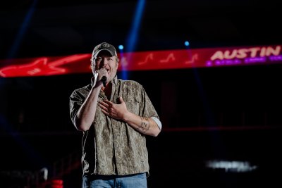 Blake Shelton wears hat and button-down shirt during performance