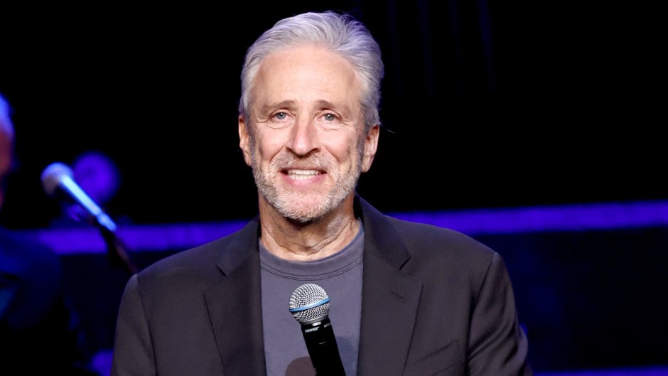 Jon Stewart smiles while holding a microphone