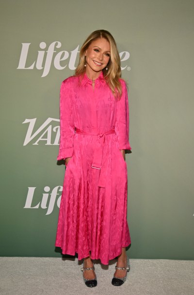 Kelly Ripa smiles in a long pink silk dress and heels