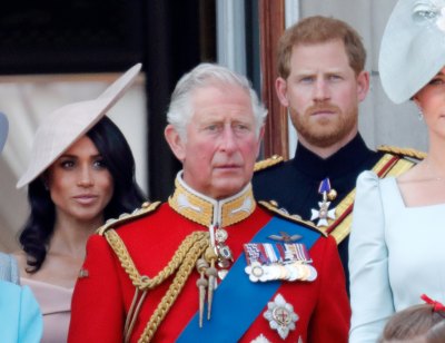 King Charles stands in front of Prince Harry and Meghan Markle