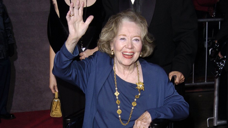 Glynis Johns waves while sitting in wheelchair