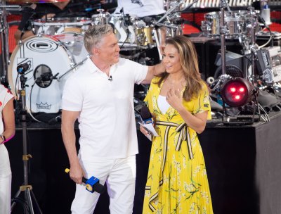 Sam Champion stands next to Ginger Zee on stage